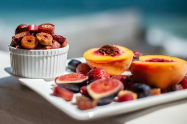 Deniz kıyısının arka planında meyve ve pastille içeren bir tabak. Nefis. Lüks.