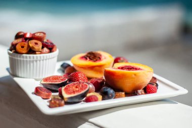 Deniz kıyısının arka planında meyve ve pastille içeren bir tabak. Nefis. Lüks.