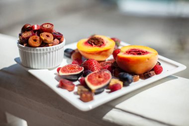 Deniz kıyısının arka planında meyve ve pastille içeren bir tabak. Nefis. Lüks.