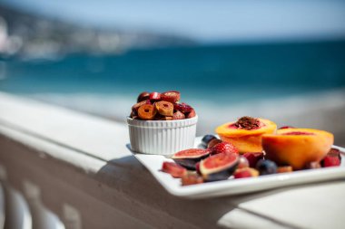 Deniz kıyısının arka planında meyve ve pastille içeren bir tabak. Nefis. Lüks.
