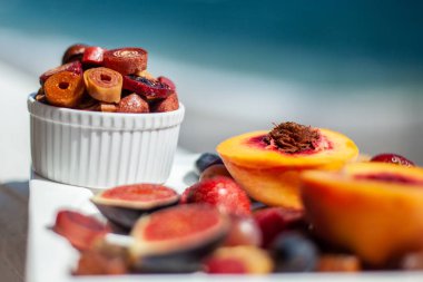 Deniz kıyısının arka planında meyve ve pastille içeren bir tabak. Nefis. Lüks.