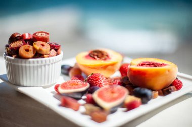 Deniz kıyısının arka planında meyve ve pastille içeren bir tabak. Nefis. Lüks.