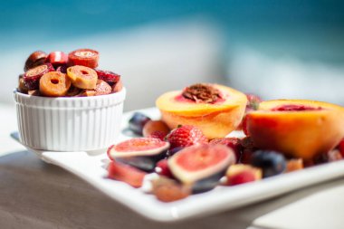 Deniz kıyısının arka planında meyve ve pastille içeren bir tabak. Nefis. Lüks.