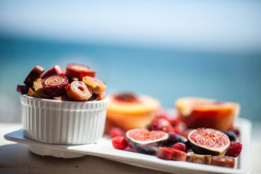 Deniz kıyısının arka planında meyve ve pastille içeren bir tabak. Nefis. Lüks.