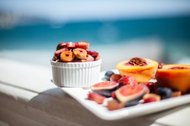 Deniz kıyısının arka planında meyve ve pastille içeren bir tabak. Nefis. Lüks.