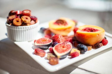 Deniz kıyısının arka planında meyve ve pastille içeren bir tabak. Nefis. Lüks.
