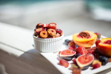 Deniz kıyısının arka planında meyve ve pastille içeren bir tabak. Nefis. Lüks.