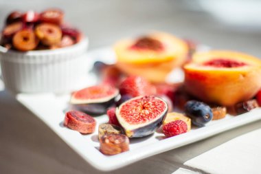 Deniz kıyısının arka planında meyve ve pastille içeren bir tabak. Nefis. Lüks.