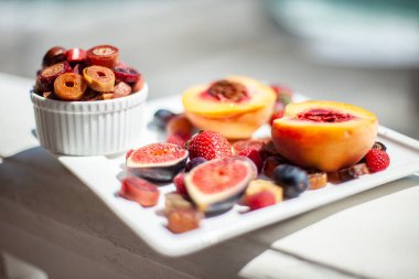 Deniz kıyısının arka planında meyve ve pastille içeren bir tabak. Nefis. Lüks.