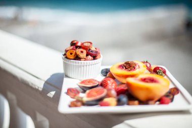 Deniz kıyısının arka planında meyve ve pastille içeren bir tabak. Nefis. Lüks.