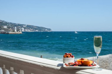 Deniz kıyısının arka planında meyve ve pastille içeren bir tabak. Nefis. Lüks.