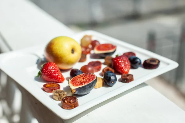 A dish with fruit and pastille on the background of the sea shore. Yummy. Luxuriously.