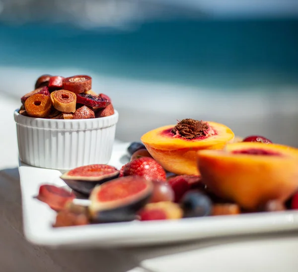 A dish with fruit and pastille on the background of the sea shore. Yummy. Luxuriously.