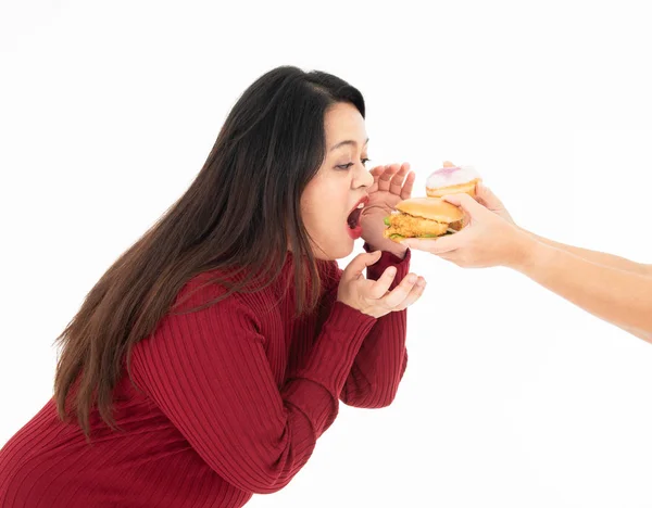 Fette hungrige Frau isst einen Hamburger und Donut. — Stockfoto