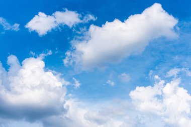 Mavi gökyüzü ve güneş ışığıyla pofuduk beyaz bulutlar.