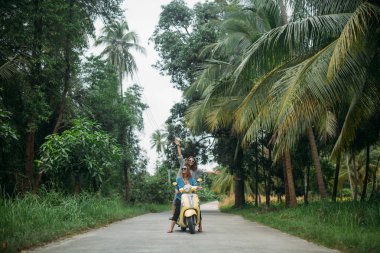 Bir çift güzel kadınların seyahat tarafından scooter Güneydoğu Asya'da ormanın içinden. Tayland