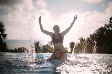 İki kız açık yüzme havuzunda güneşli bir günde bir tropik adada oynamak.