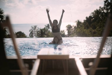 Güneşli bir günde açık yüzme havuzunda oynayan iki kız 