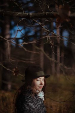 Genç bir kadın, güneşli bir günde sonbahar Ormanda yürür. Bir kız bir palto ve şapka ağaçların dallarında portresi
