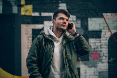 Cityscape zemin karşı telefonda konuşan bir adam. Genç işadamı tarafından cep telefonu endüstriyel yatay olarak iletişim kurar