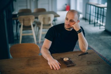 Genç bir adam bir kafede oturuyor. Adam restoranda sipariş için bekliyor