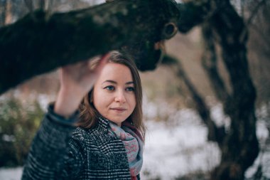 Genç bir kadın bir kış parkta yürüyor. Yalnız kışın güzel kızın ağaçları arasında yürüyor