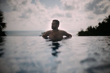 Açık Yüzme havuzunda bir genç yakışıklı bir adam portresi. Havuzun kenarındaki sakallı çekici adam