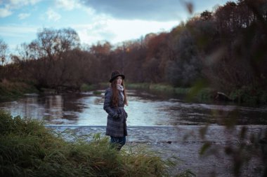 Bir kız bir bulutlu üzerinde köprü nehir kıyısında duruyor
