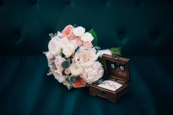 Anillos de boda en una caja de madera y ramo de novia — Foto de Stock