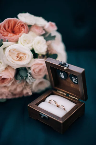 Anéis de casamento em uma caixa de madeira e buquê de noiva — Fotografia de Stock