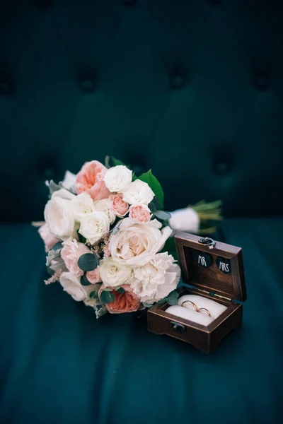 Anillos de boda en una caja de madera y ramo de novia — Foto de Stock