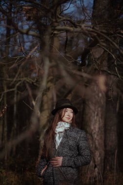 Genç bir kadın güneşli bir günde sonbahar ormanda yürür.