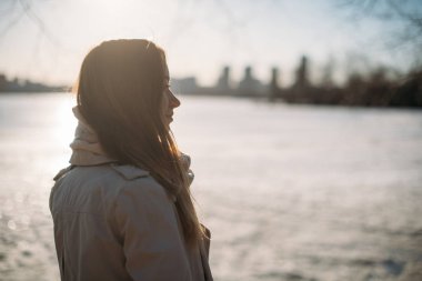 Kız baharda donmuş gölde duruyor.
