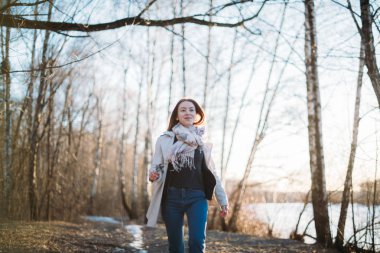 Bir kız son karda bir orman izi boyunca yürür.