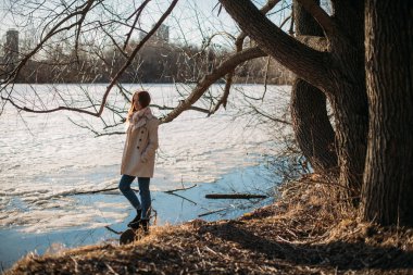 Kız baharda donmuş gölde duruyor.