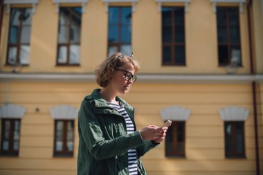 Elinde telefonla yol arayan genç bir turist. 