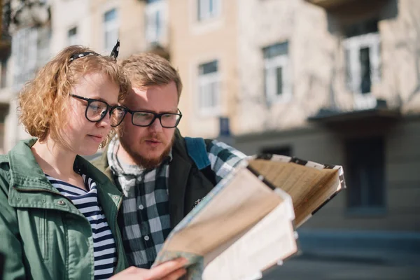 Un jeune couple de touristes sont à la recherche d'une route avec une carte en — Photo