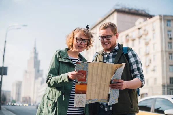 A young couple of tourists are looking for a road with a map in