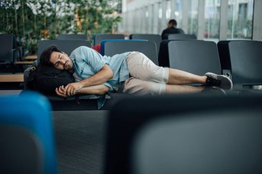 Havaalanındaki adam kalkışı bekliyor, uyuyor.