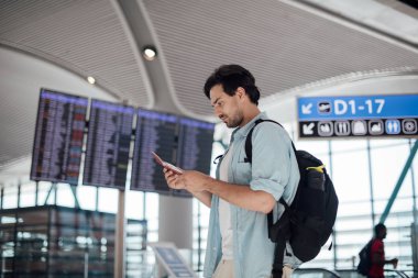 Havaalanında kalkış bekleyen adam, program aranıyor. 