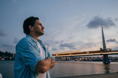 Şehrin arka planda rıhtımda gün batımında bir adam.