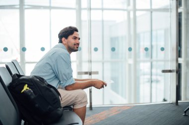 Sırt çantalı adam havaalanında oturuyor.. 