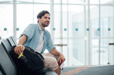 Sırt çantalı adam havaalanında oturuyor.. 