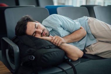 Havaalanındaki adam kalkışı bekliyor, uyuyor.