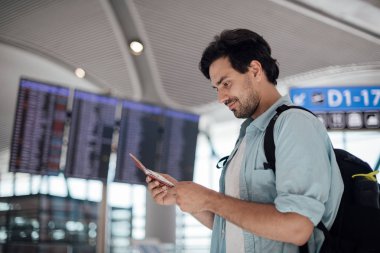 Havaalanında kalkış bekleyen adam, program aranıyor. 