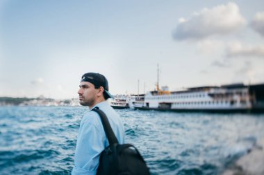 Denizin arka planına karşı genç bir adamın portresi, şehir,