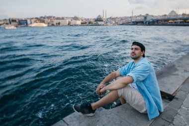 Denizin arka planına karşı genç bir adamın portresi, şehir,