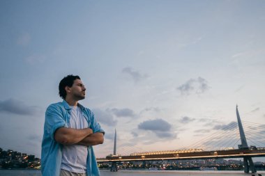 Şehrin arka planda rıhtımda gün batımında bir adam.