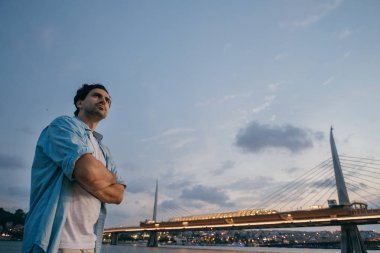 Şehrin arka planda rıhtımda gün batımında bir adam.