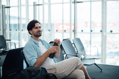 Havaalanında kalkış bekleyen adam, içme suyu. 